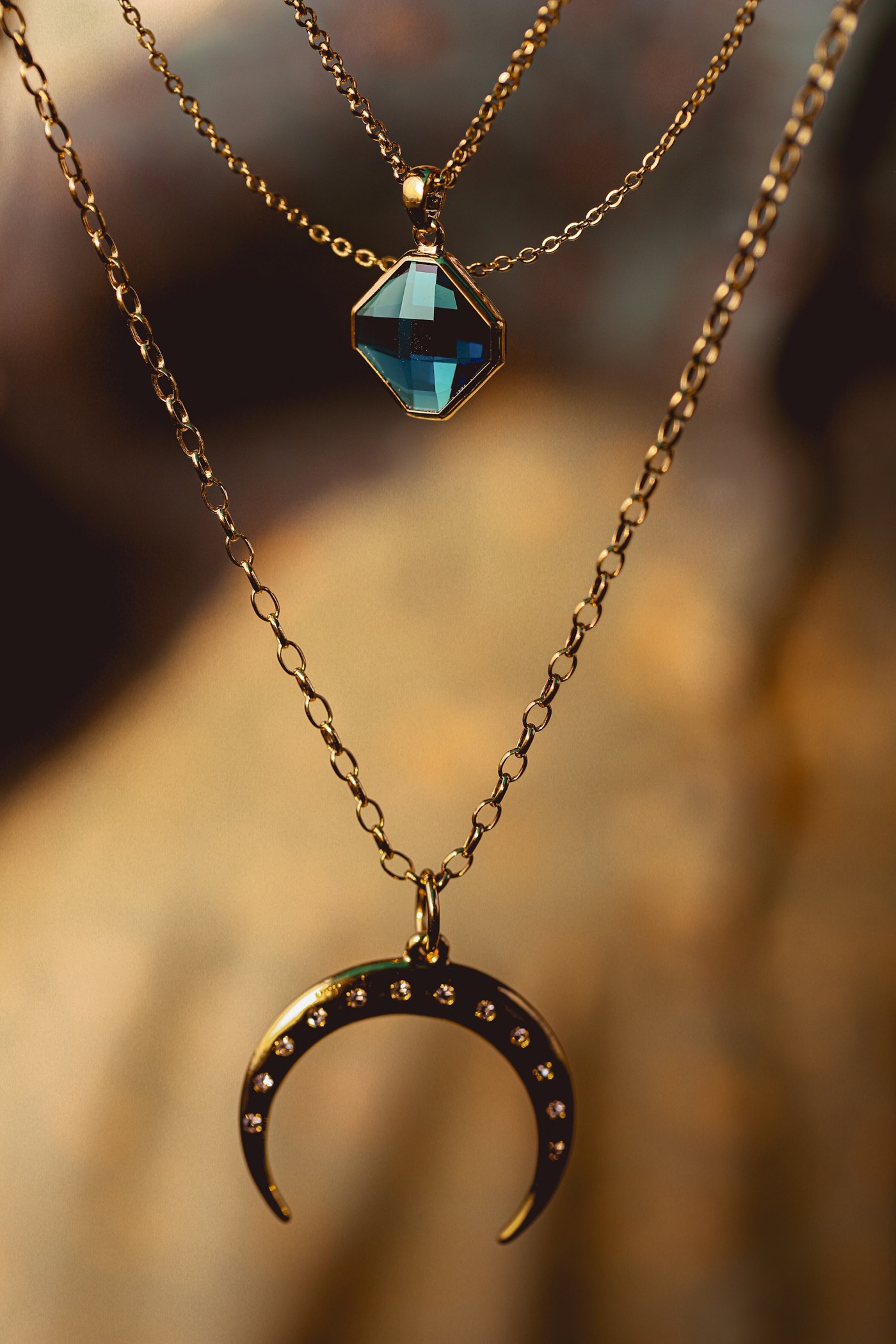 Layered gold necklaces with a midnight-blue moissanite pendant
